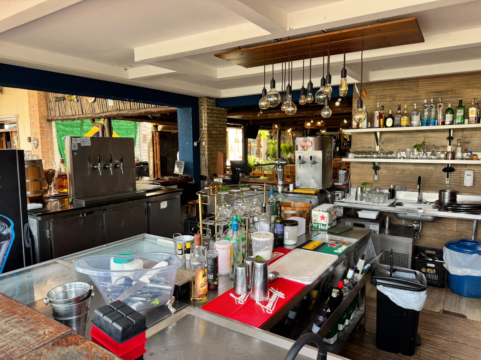 Estação de preparo do bar com torres de chope, lâmpadas Edison e prateleira de garrafas