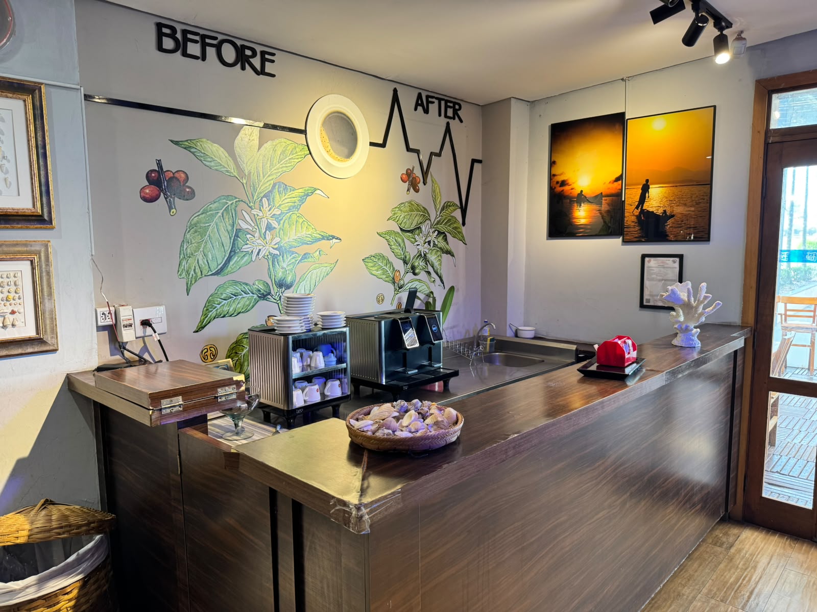 Balcão de madeira do café com máquina de café, xícaras e mural com folhas e grãos