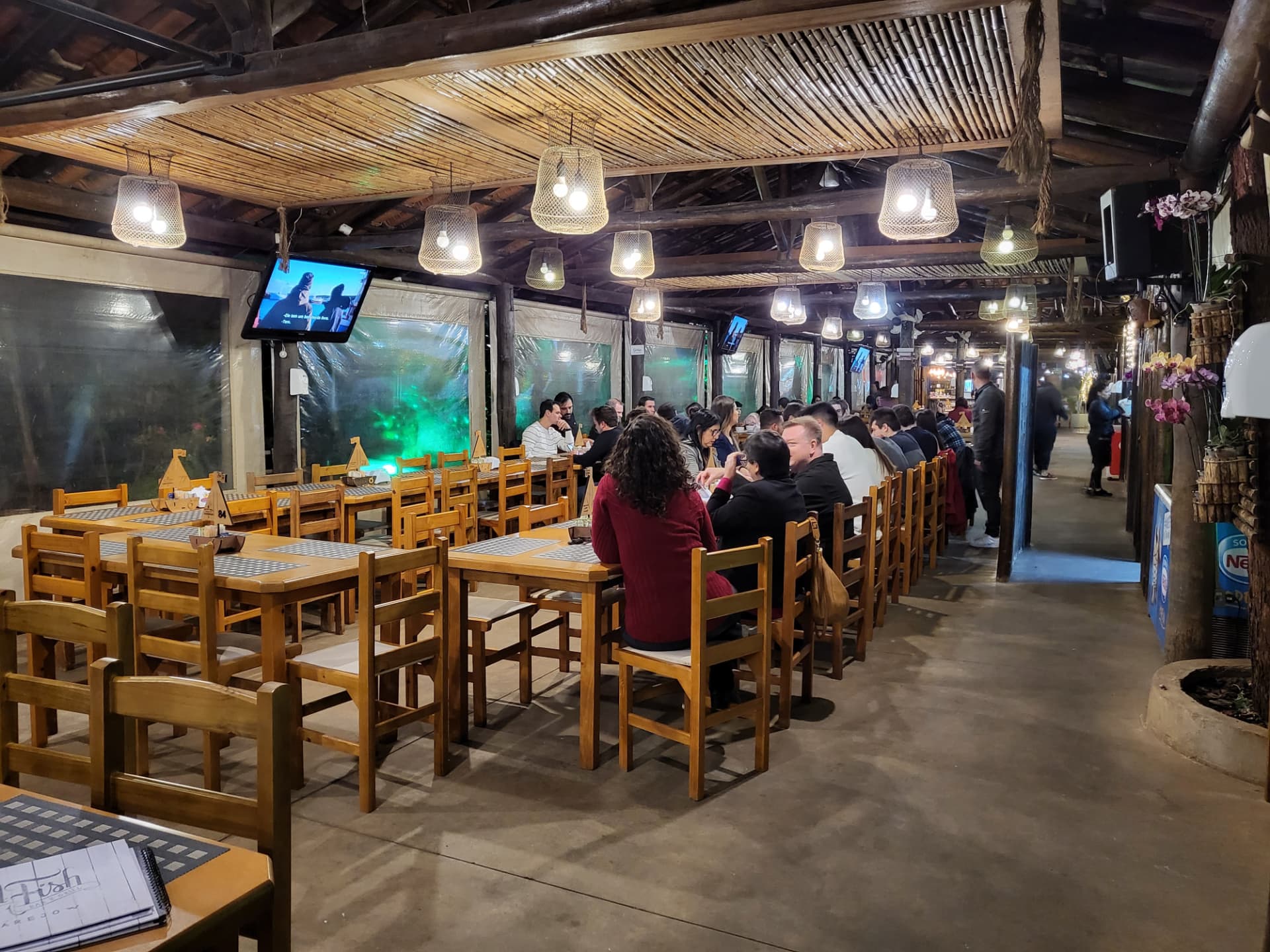 Salão rústico aberto com teto de bambu e luminárias cesto
