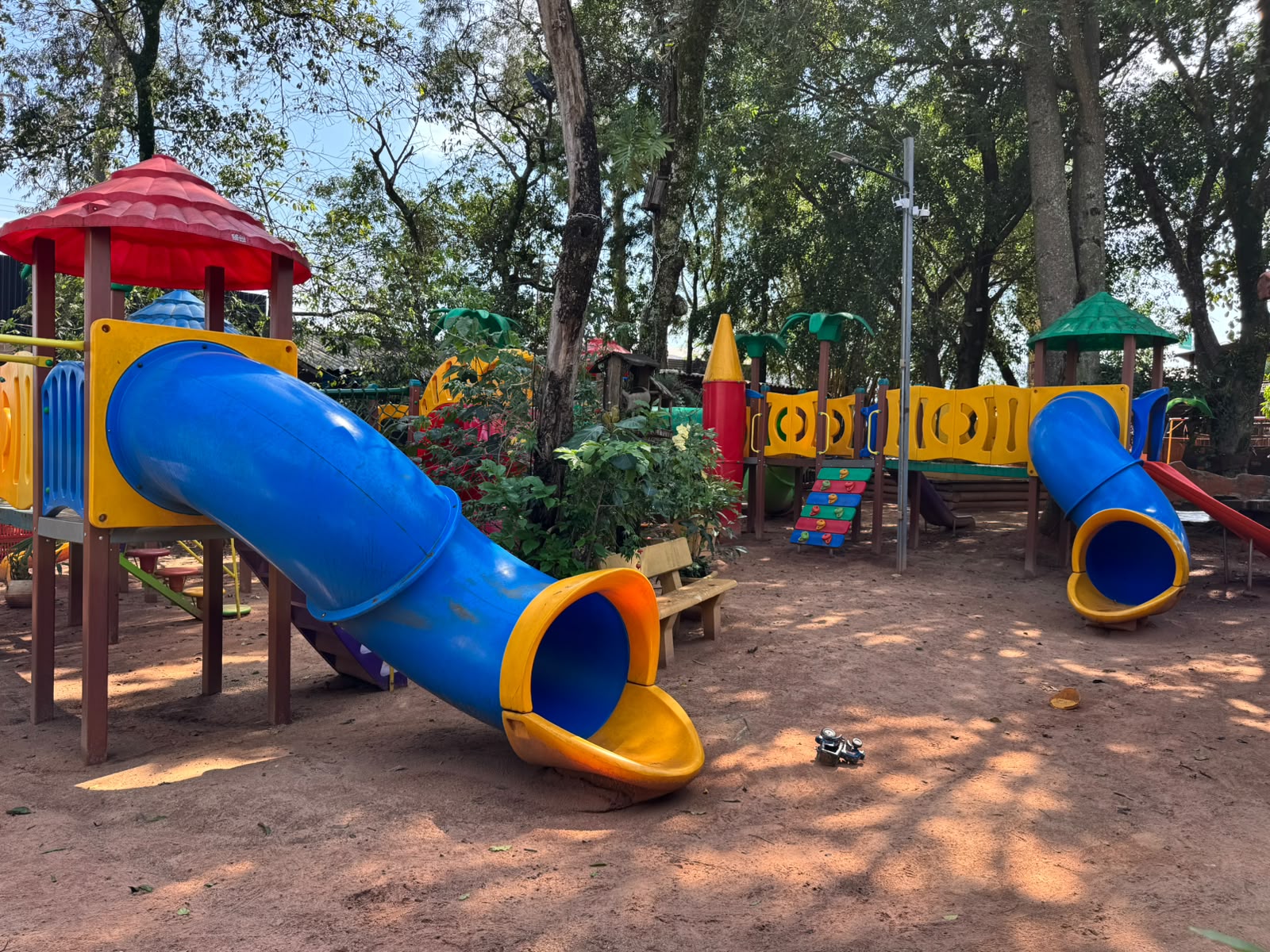 Estrutura de brinquedos colorida com escorregador tubular azul, teto vermelho e painéis amarelos