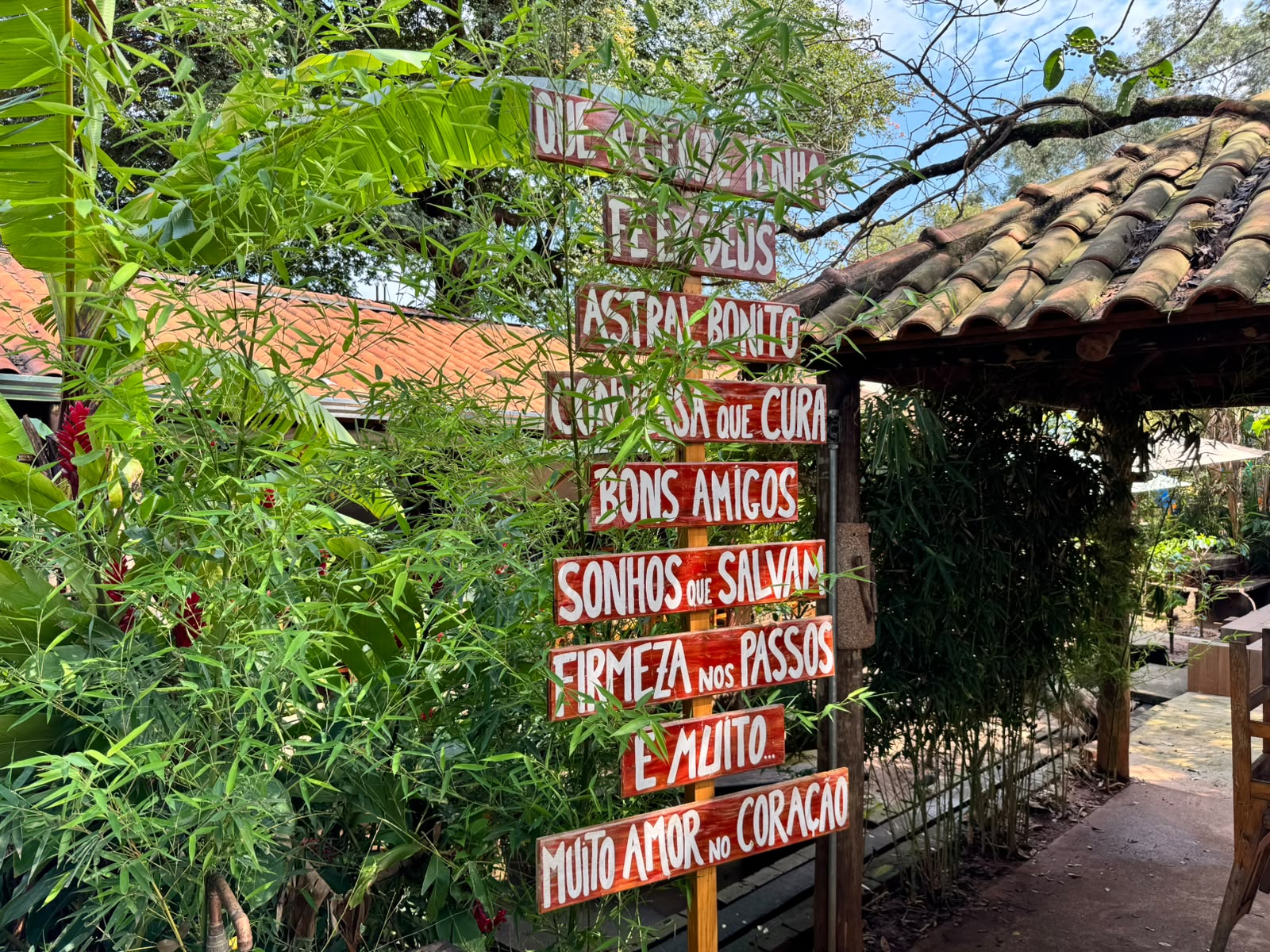 Totem decorativo de madeira com mensagens positivas entre bambus e estruturas de quiosque